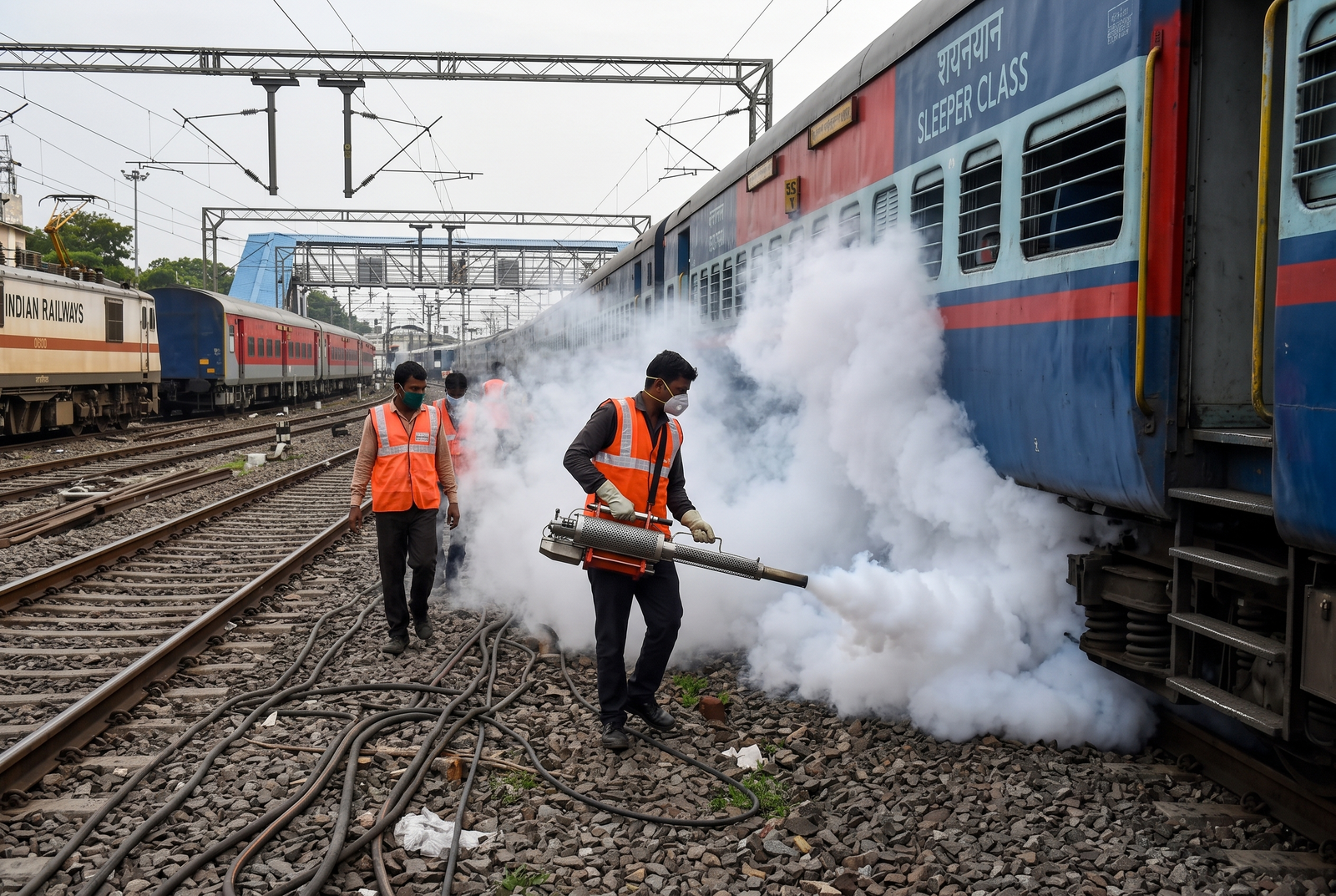 Railway engineer with safety helmet and protective gear inspecting train equipment in workshop